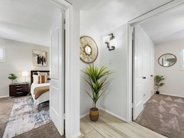 Un dormitorio con cama, mesita de noche, lámpara y un ventilador de pared.