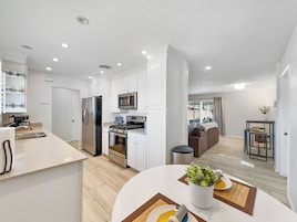 Una cocina moderna con armarios blancos, electrodomésticos de acero inoxidable y una isla central.