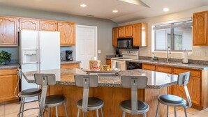 A modern kitchen with wooden cabinets, granite countertops, and a central island with bar stools. - Lookout Payson (Payson)