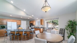 A modern kitchen with wooden cabinets, a central island with stools, and a dining area with a round table and chairs. - Lookout Payson (Payson)