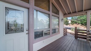 A covered porch with a wooden floor, large windows, and a white door with a glass panel. - Lookout Payson (Payson)