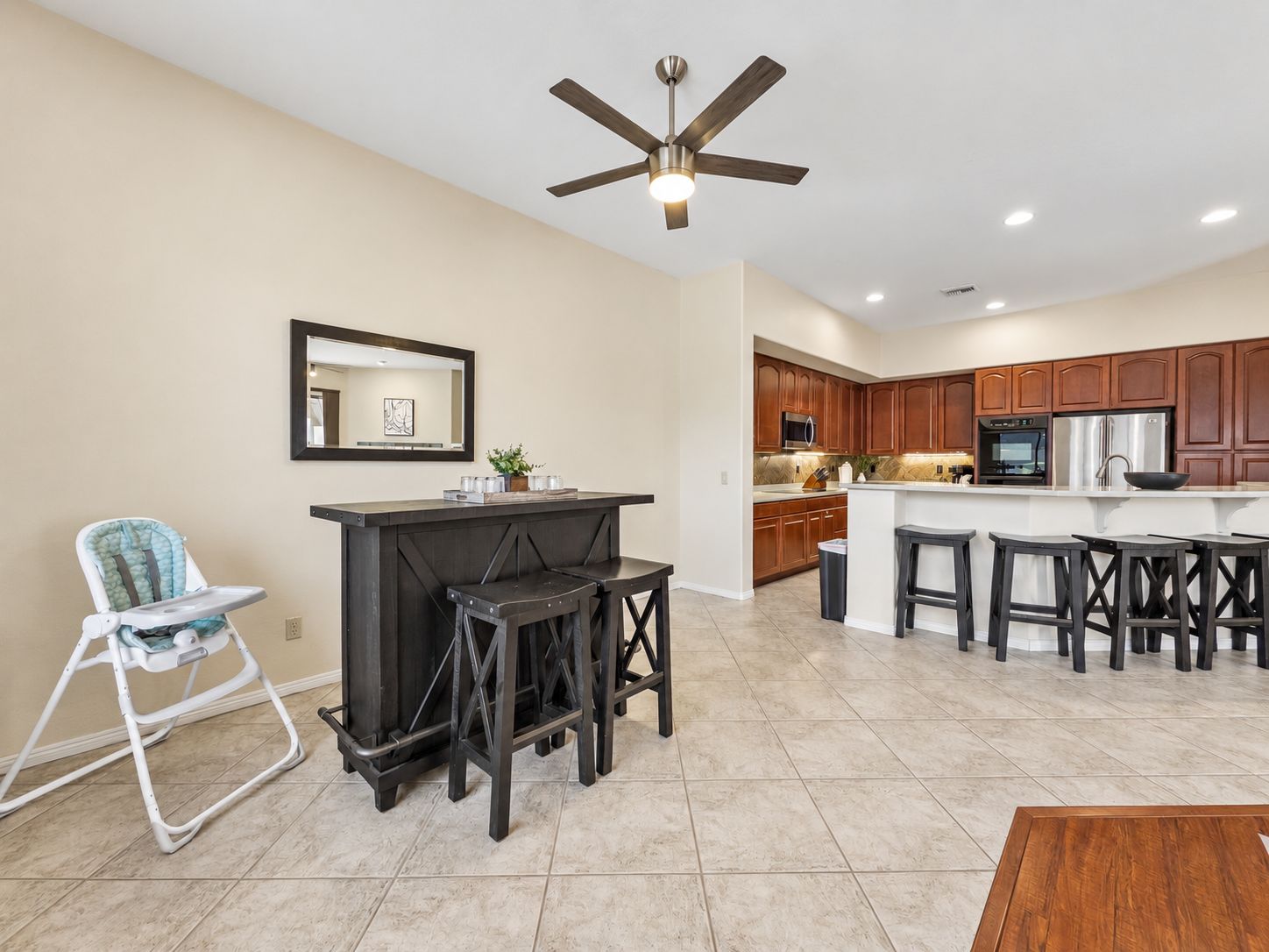 A modern kitchen with wooden cabinets, a central island, and a ceiling fan.