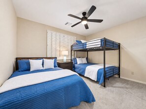 A bedroom with two bunk beds, a ceiling fan, a bedside table with a lamp, and a window with blinds. - Lynx Chandler/ocotillo (Chandler)