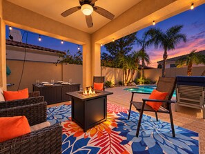 Una terrazza esterna con piscina, sedie a sdraio, un braciere e una ventola a soffitto.