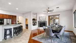 A modern kitchen with a central island, a dining area with a large table and chairs, and a fireplace. - Lynx Chandler/ocotillo (Chandler)