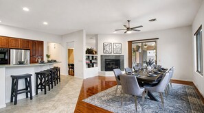 A modern kitchen with a central island, a dining area with a large table and chairs, and a fireplace. - Lynx Chandler/ocotillo (Chandler)