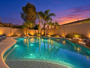 A swimming pool with a curved edge, surrounded by palm trees and a low wall. - Lynx Chandler/ocotillo (Chandler)