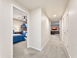 A hallway leading to a bedroom with bunk beds, a ceiling fan, and a TV in the adjacent living area. - Lynx Chandler/ocotillo (Chandler)