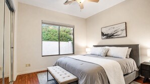 A bedroom with a bed, bench, bedside tables, a ceiling fan, and a window with blinds. - Lynx Chandler/ocotillo (Chandler)