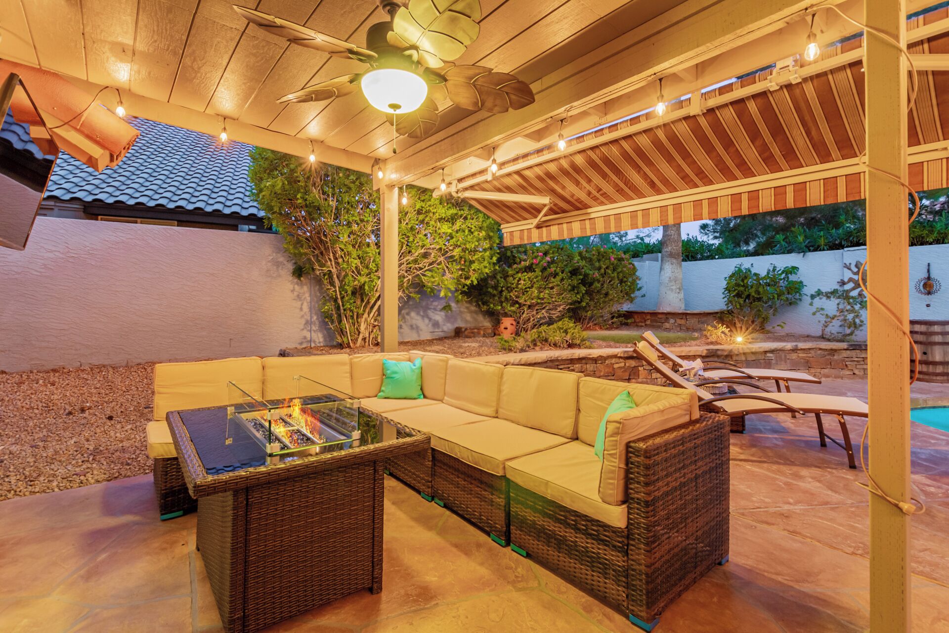 Eine Terrassengruppe mit Rattan-Sofa, Tisch mit Glasplatte und Deckenventilator.