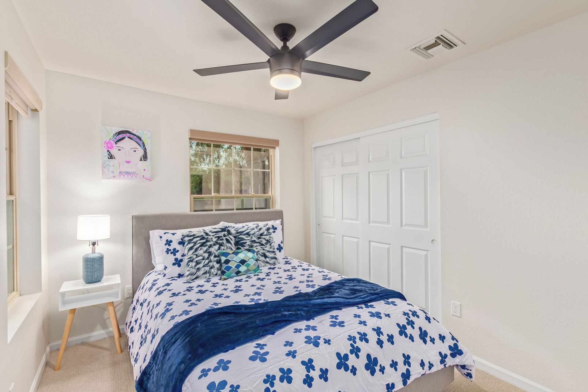 A bedroom with a bed, a ceiling fan, a window, and a door.