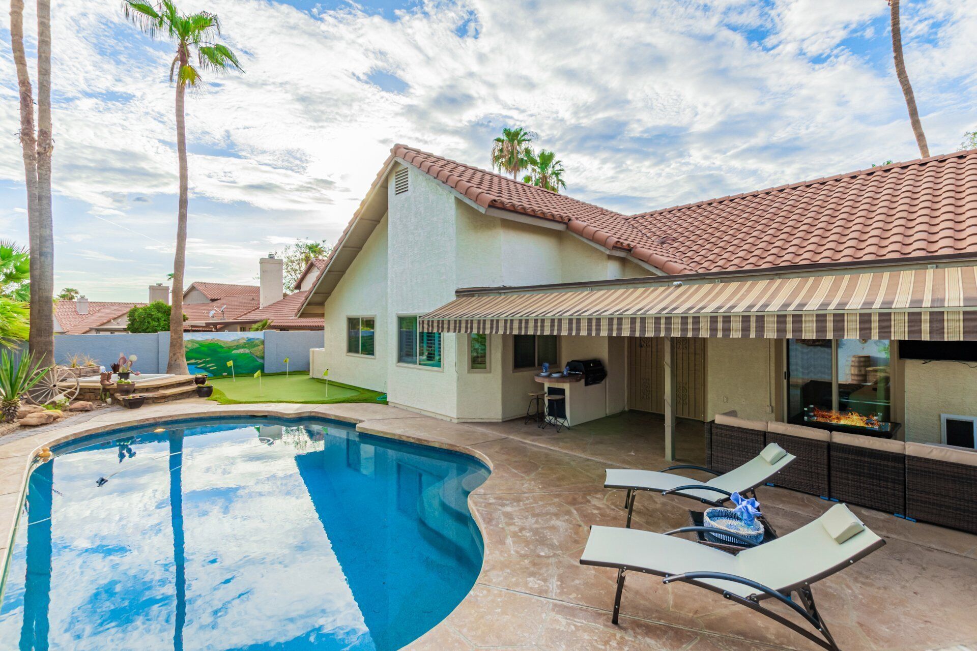 A house with a swimming pool, outdoor seating, and a patio area.