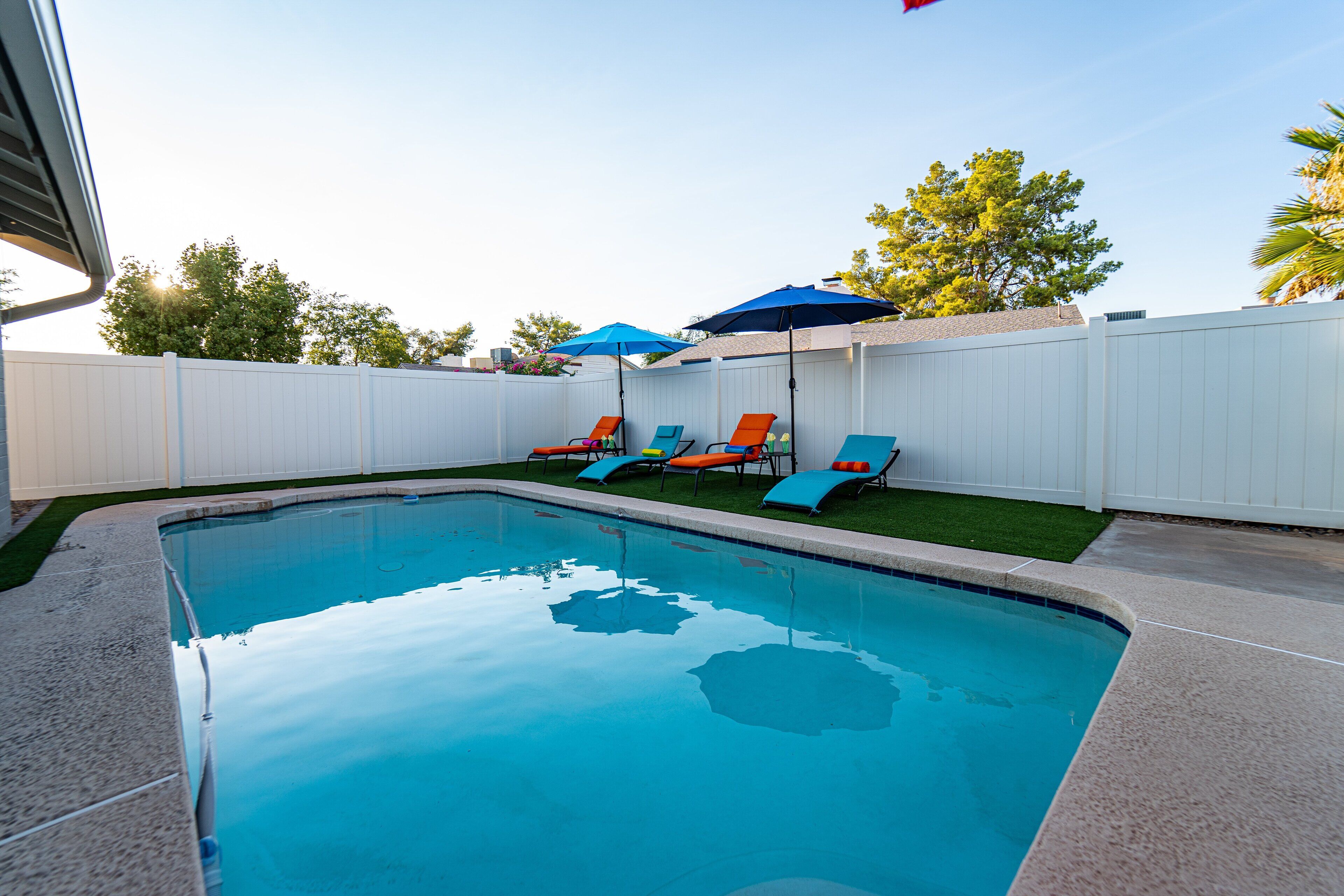 A rectangular swimming pool with a white fence in the background.
