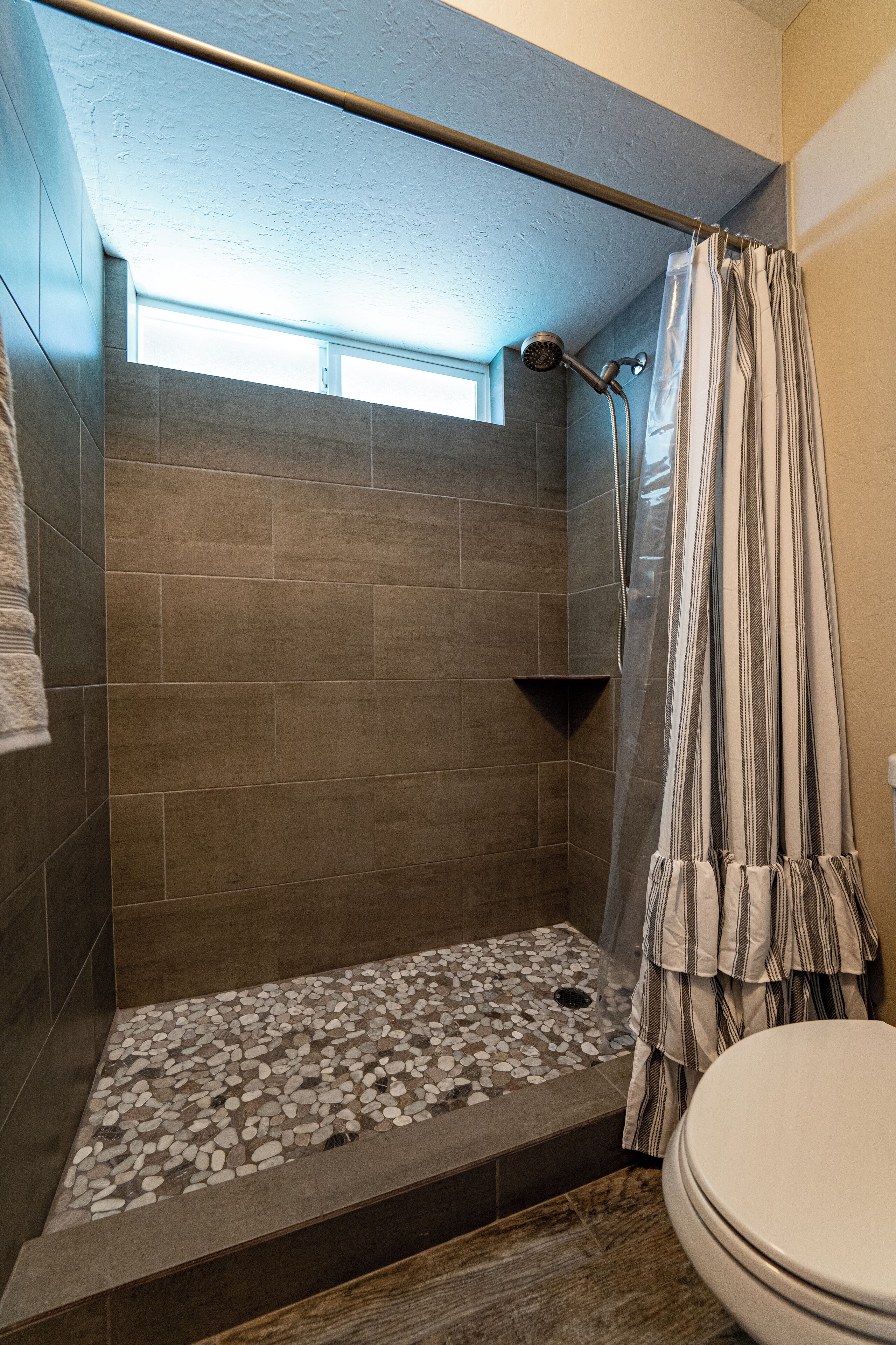 Un espace douche avec un sol carrelé, une pomme de douche et un rideau.