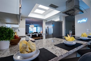 Una cocina moderna con encimeras de granito, electrodomésticos de acero inoxidable y un letrero de neón.