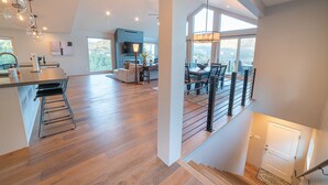 A spacious kitchen with a modern design, a dining area with a view, and a staircase leading to an upper level. - Ruin Hill Kokopeli Pine (Pine)