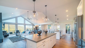 A spacious kitchen with a large island, modern pendant lights, and a view of the outdoors. - Ruin Hill Kokopeli Pine (Pine)