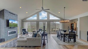 A spacious living room with a large TV, a fireplace, and a dining area with a chandelier. - Ruin Hill Kokopeli Pine (Pine)