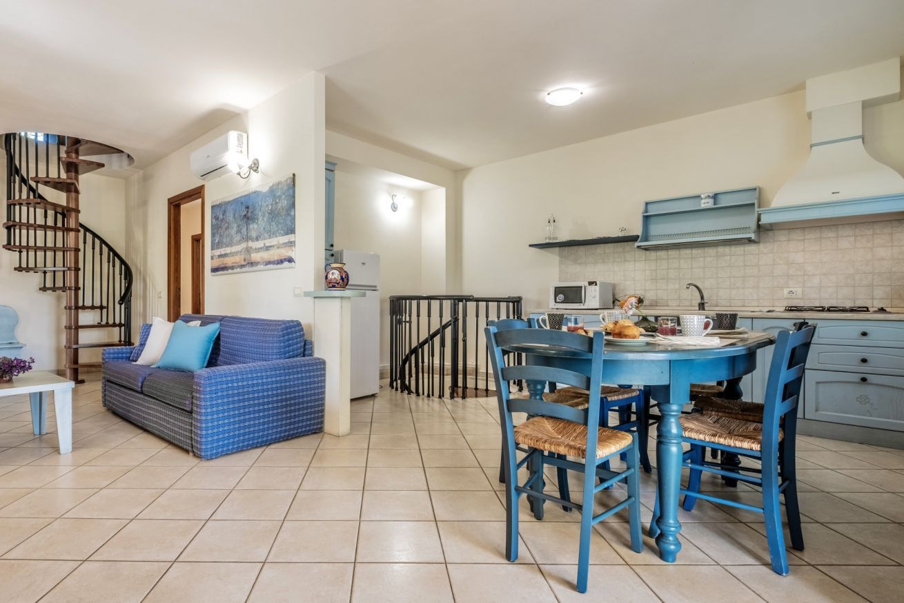 A compact living space with a kitchen, dining area, and a staircase leading to another level.