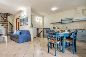 Een compacte leefruimte met keuken, eethoek en een trap naar een ander niveau.