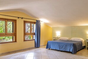 A bedroom with a bed, a nightstand, a lamp, and a window with curtains.