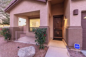 A two-story building with a covered entrance, a gated front door, and a security sign. - Merino Mesa (Mesa)