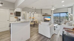 A modern living room with a white sofa, a dining area, and a kitchen with a marble island. - Saguaro #202 Fountain Hills (Fountain Hills)