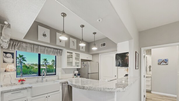 A modern kitchen with white cabinetry, a marble countertop, and pendant lighting. - Saguaro #202 Fountain Hills (Fountain Hills)