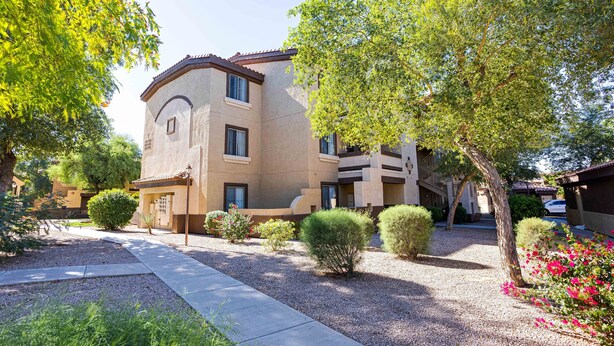 A multi-story building with a beige facade, surrounded by well-maintained landscaping, including trees and shrubs. - Southern #2068 Mesa (Mesa)