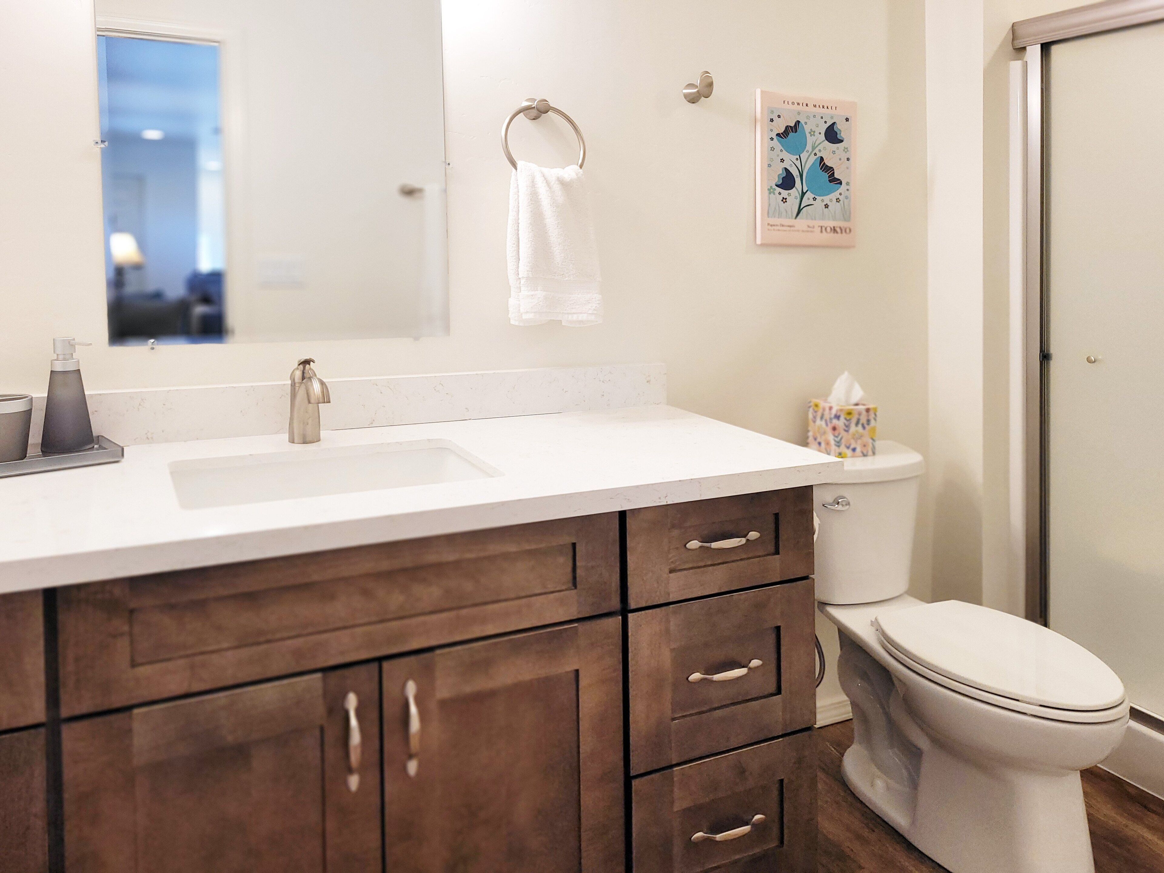 A bathroom with a white sink, dark wooden cabinets, a toilet, and a shower.