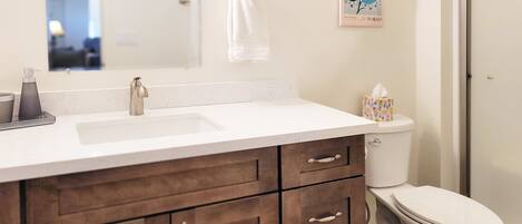 A bathroom with a white sink, dark wooden cabinets, a toilet, and a shower.