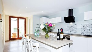 A modern kitchen with a central island, white cabinetry, and a black range hood.