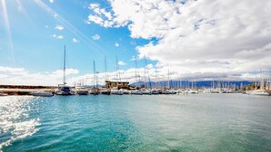 A marina with numerous sailboats docked, calm water, and a clear sky with some clouds.