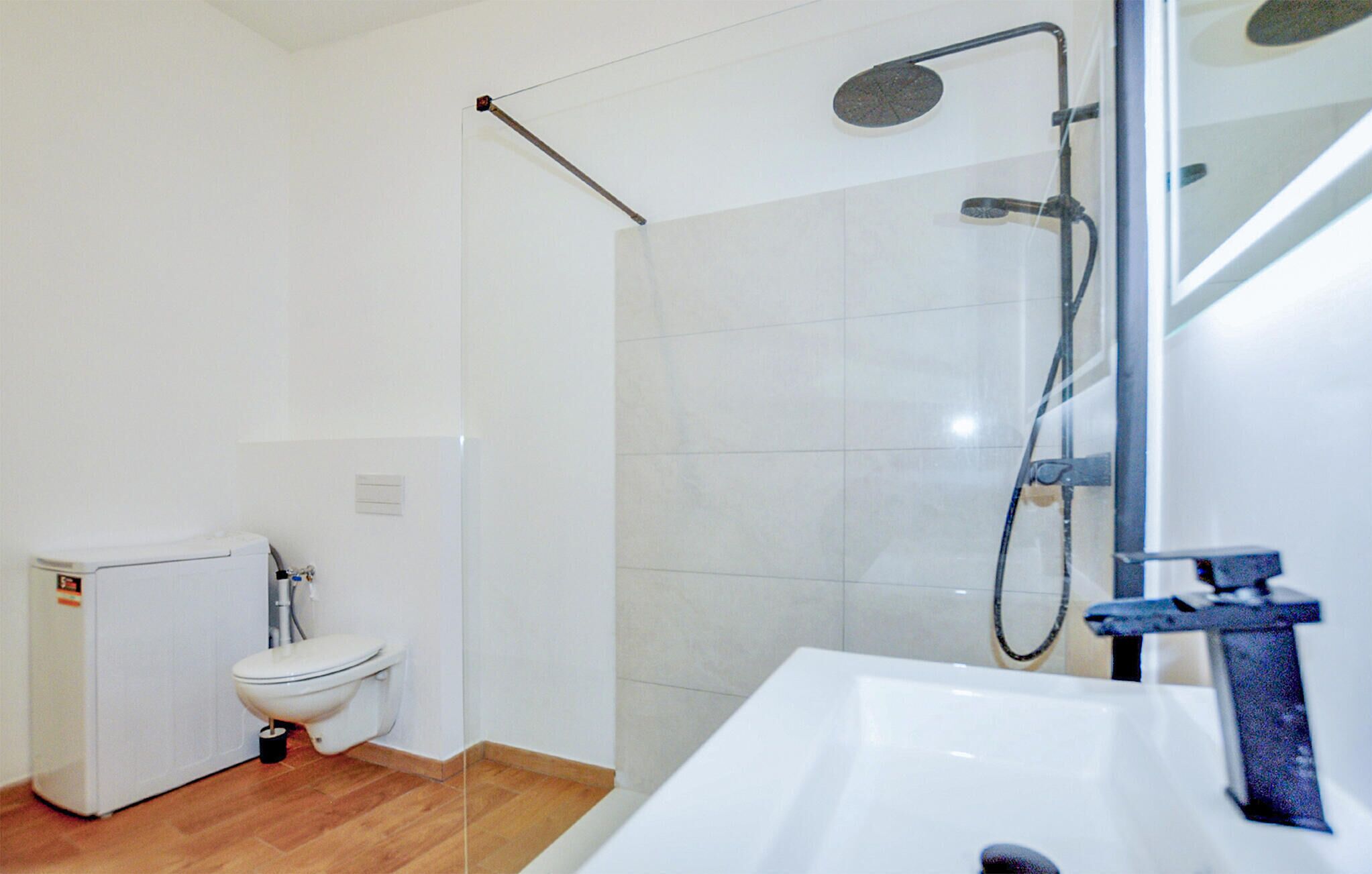 A bathroom with a toilet, a shower with a glass door, and a sink.