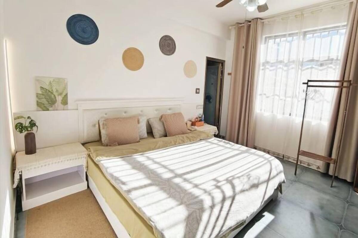 Une chambre à coucher avec un lit, une table de chevet, des rideaux et une fenêtre.