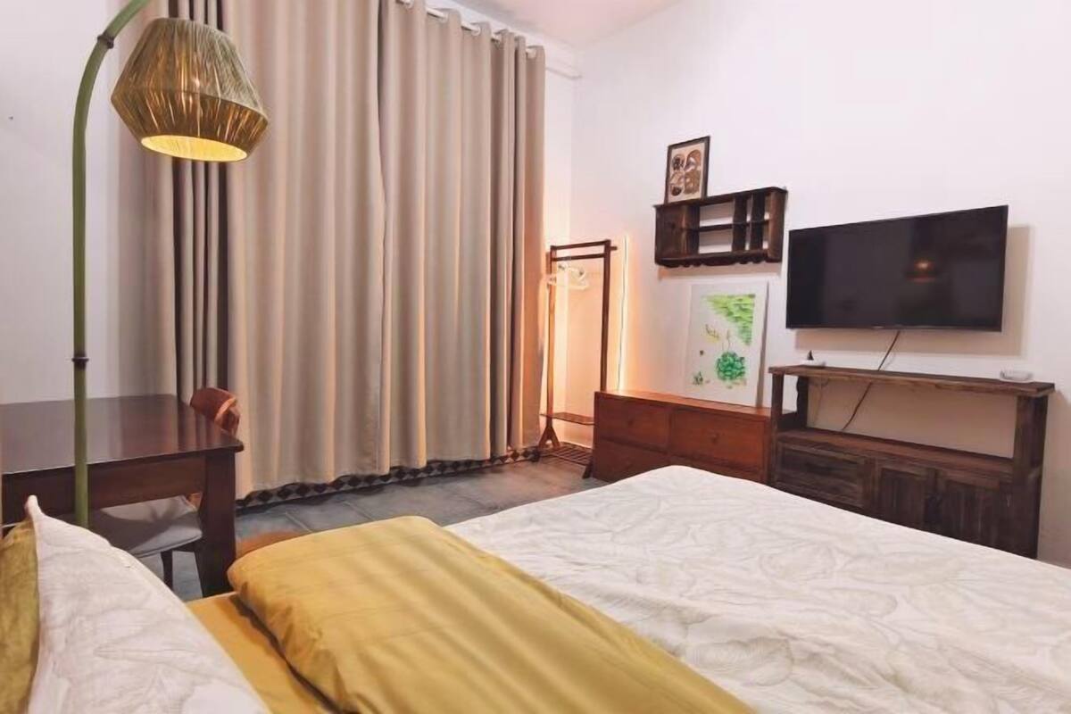 Une chambre d’hôtel avec un lit, un bureau, une chaise, une télévision et une lampe.