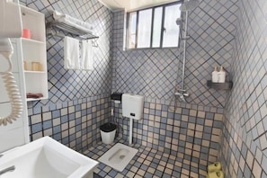 A bathroom with a tiled floor, a toilet, a sink, a shower, and a window. - Walking Flowers Inn (Dali City)