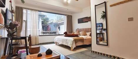 Un dormitorio con una cama, ventilador de techo, ventana y espejo en la pared.