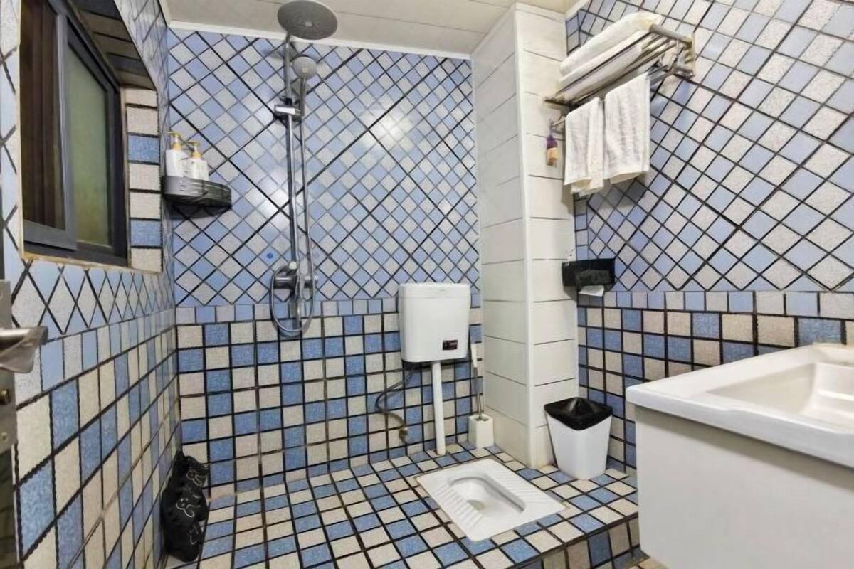 Une salle de bain avec une douche, des toilettes, un lavabo et un mur carrelé.