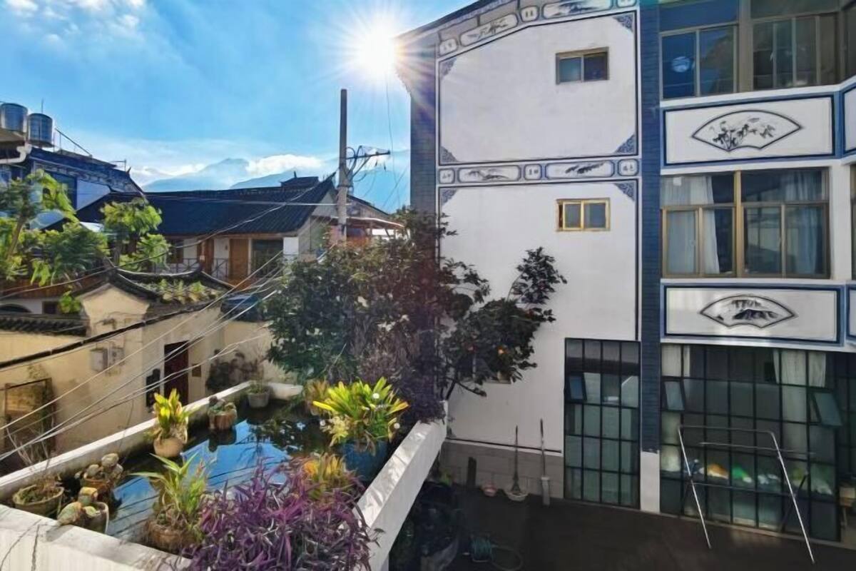 Un bâtiment à la façade blanche, ornée de motifs décoratifs, et doté d’un balcon où sont disposées des plantes en pot.