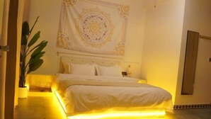 Un dormitorio con una cama, un tapiz grande en la pared y una planta en maceta.