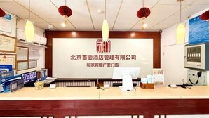 Un comptoir d’accueil d’hôtel avec une grande enseigne, un ordinateur et divers documents d’information.