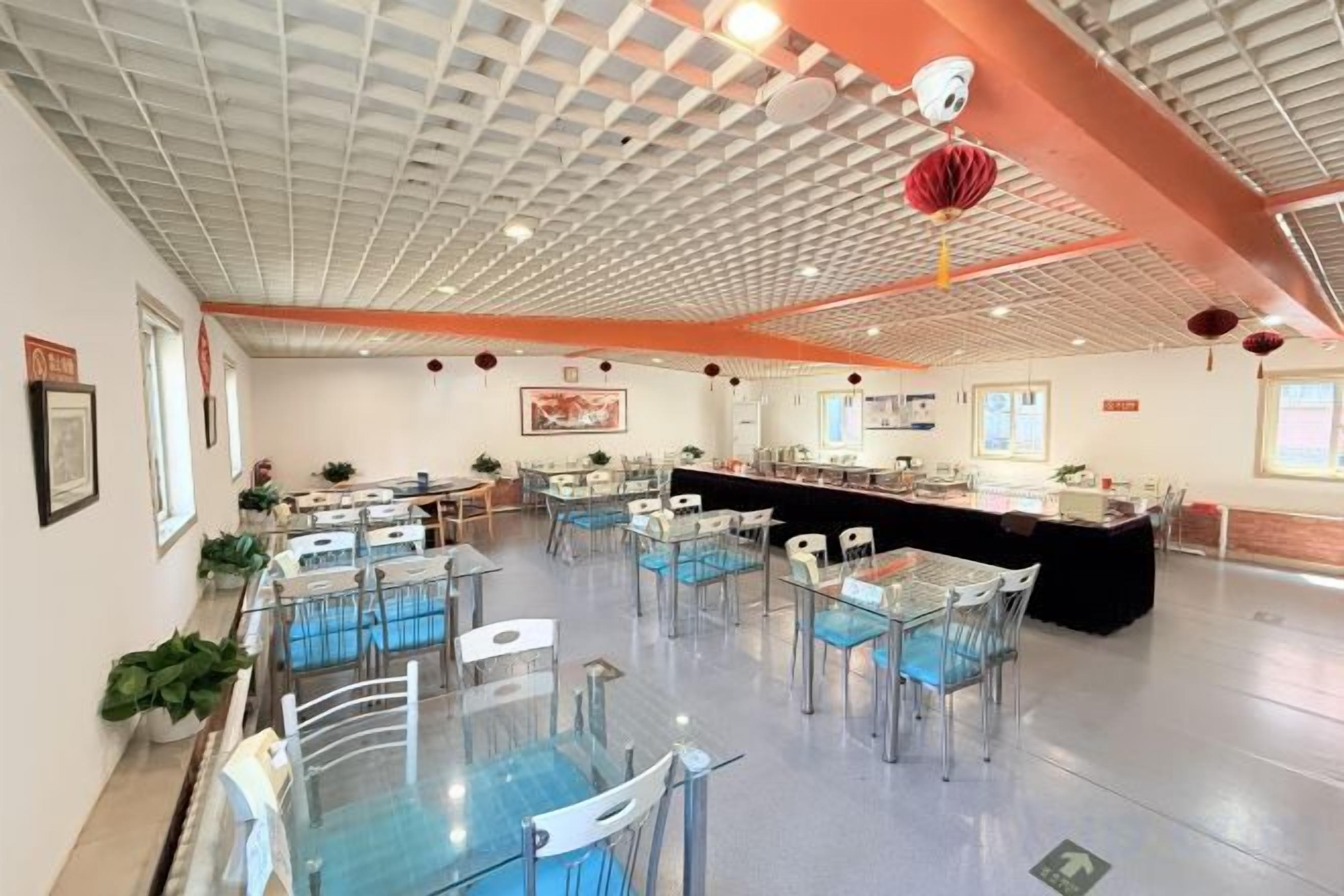 Un espacio interior amplio con varias mesas y sillas, una barra y un techo con diseño de cuadrícula.