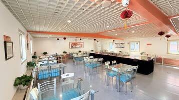Un espacio interior amplio con varias mesas y sillas, una barra y un techo con diseño de cuadrícula.
