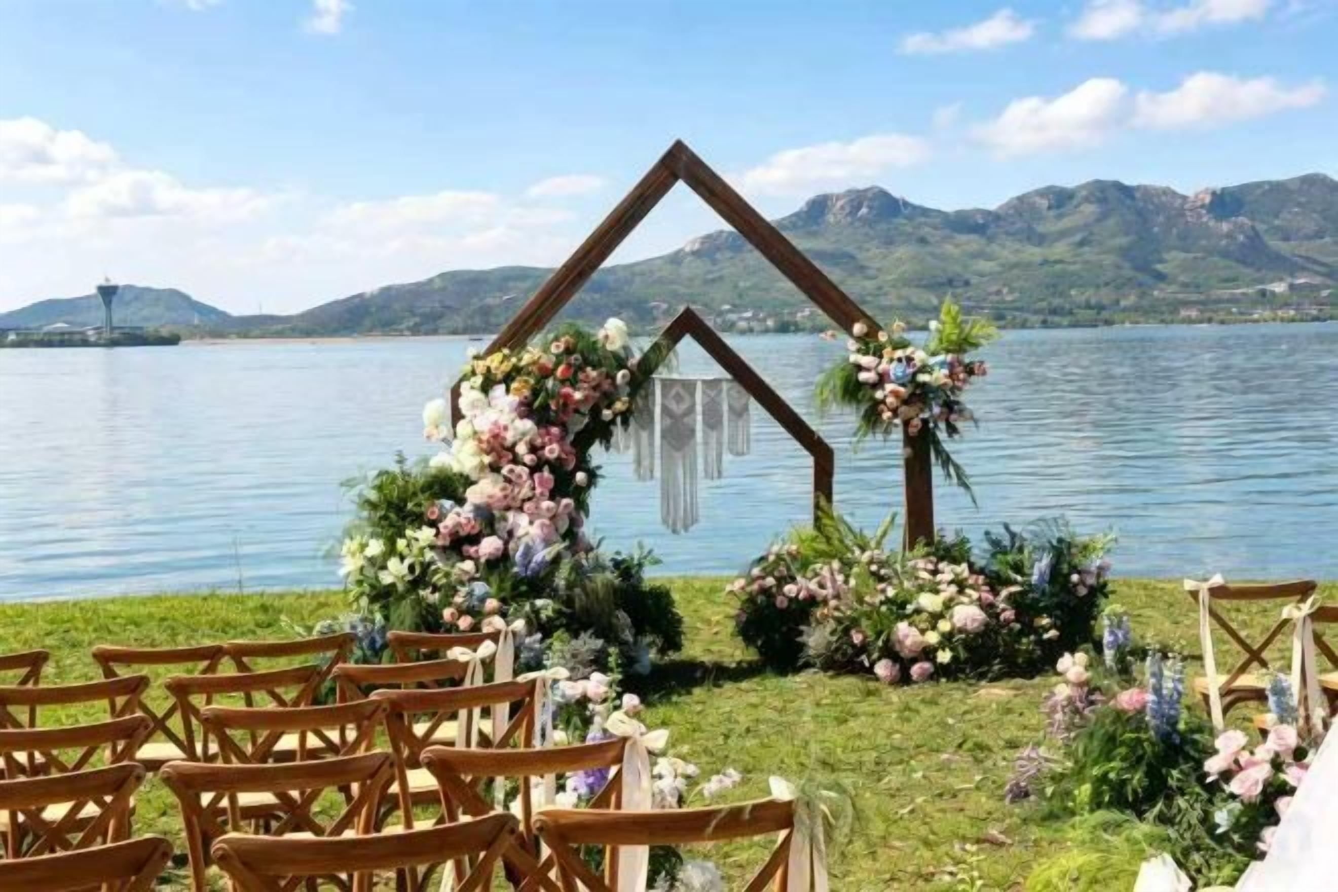 A lakeside wedding setup with a wooden arch and floral decorations.