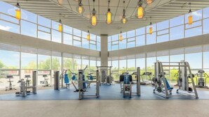 A spacious gym with large windows and ceiling lights. - Wei Select Xueye Hotel (Jinan)