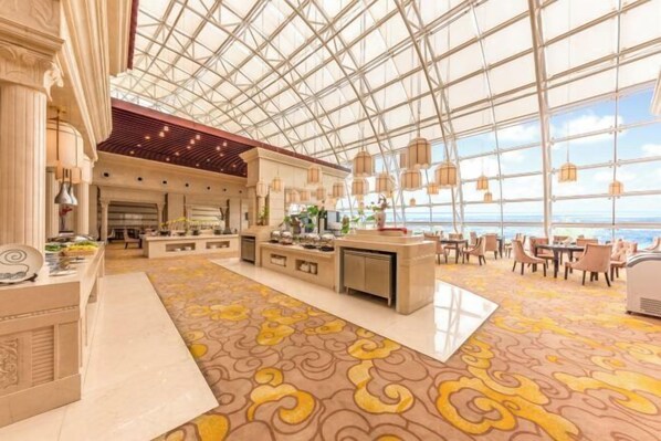 Eine geräumige Hotelhalle mit hoher Decke, großen Fenstern und einem gemusterten Teppich.