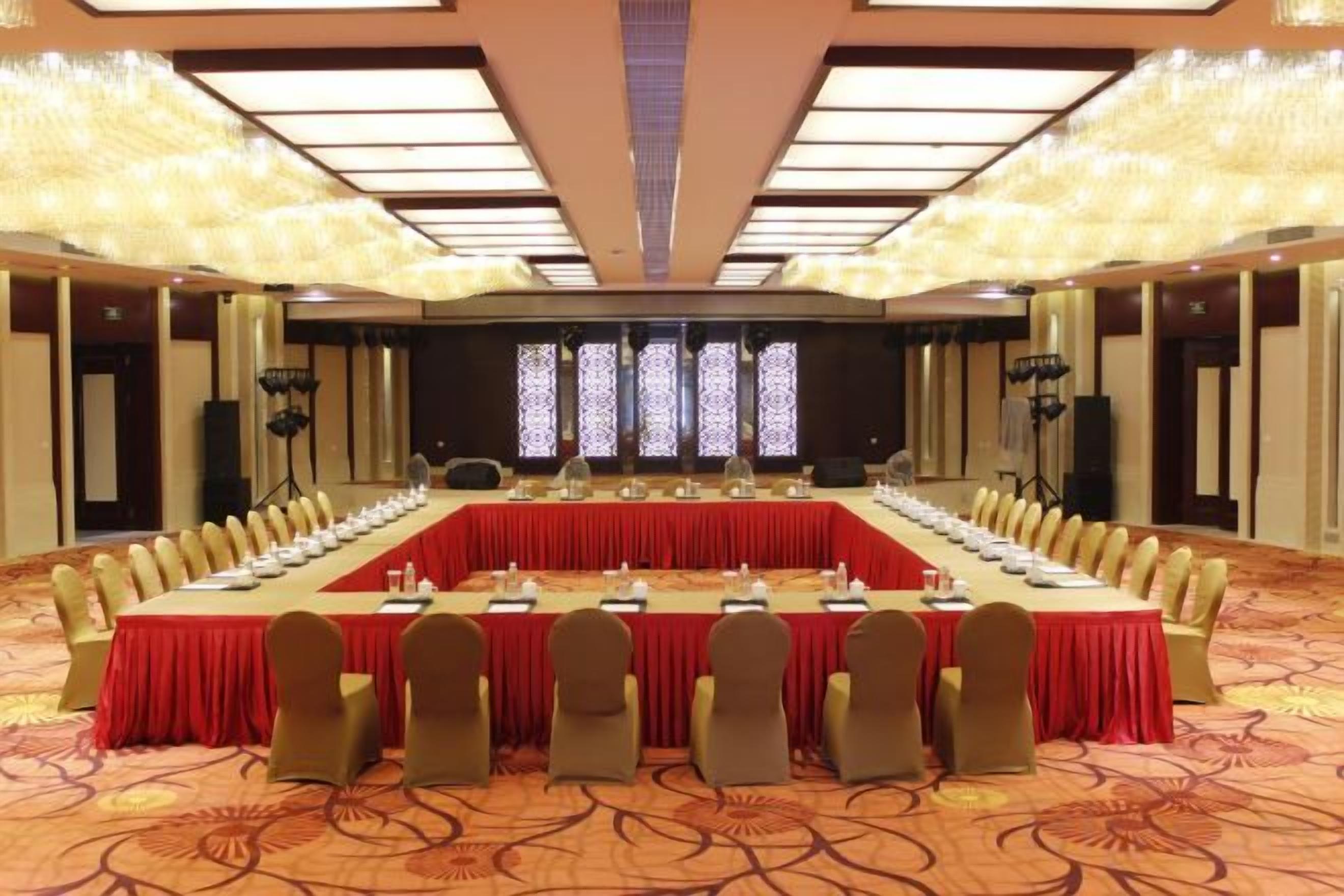 A conference room with a long table, chairs, and a stage with a screen.