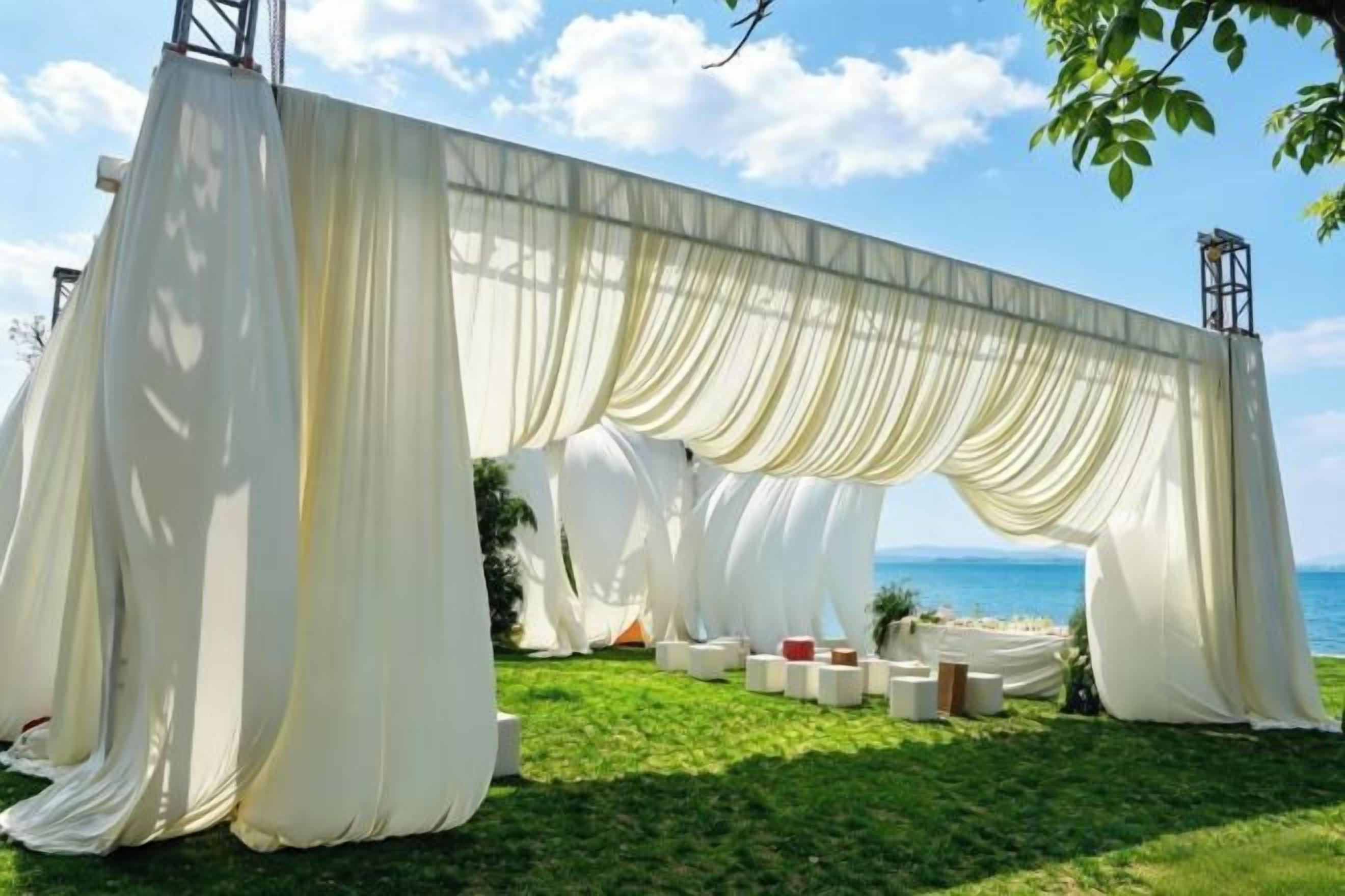 A white draped structure with a view of the sea.