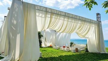 A white draped structure with a view of the sea.